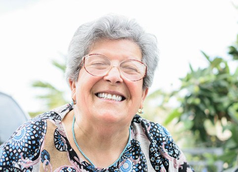 Woman sitting outside and smiling brightly
