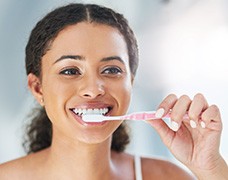 Closeup of woman smiling while brushing her teeth