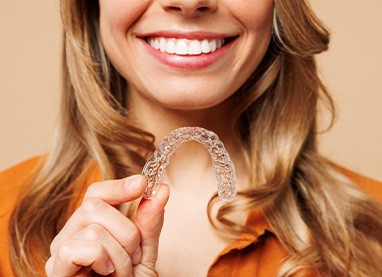 Patient smiling while holding clear aligner