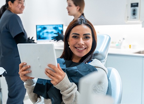 Woman smiling while holding handheld mirror
